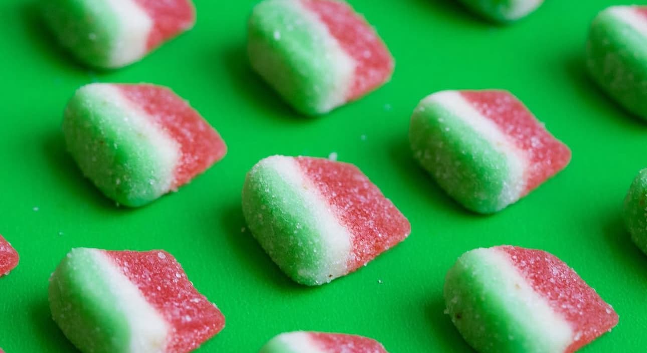 Jolly Green Oil red, white, and green watermelon-style gummies on a green background